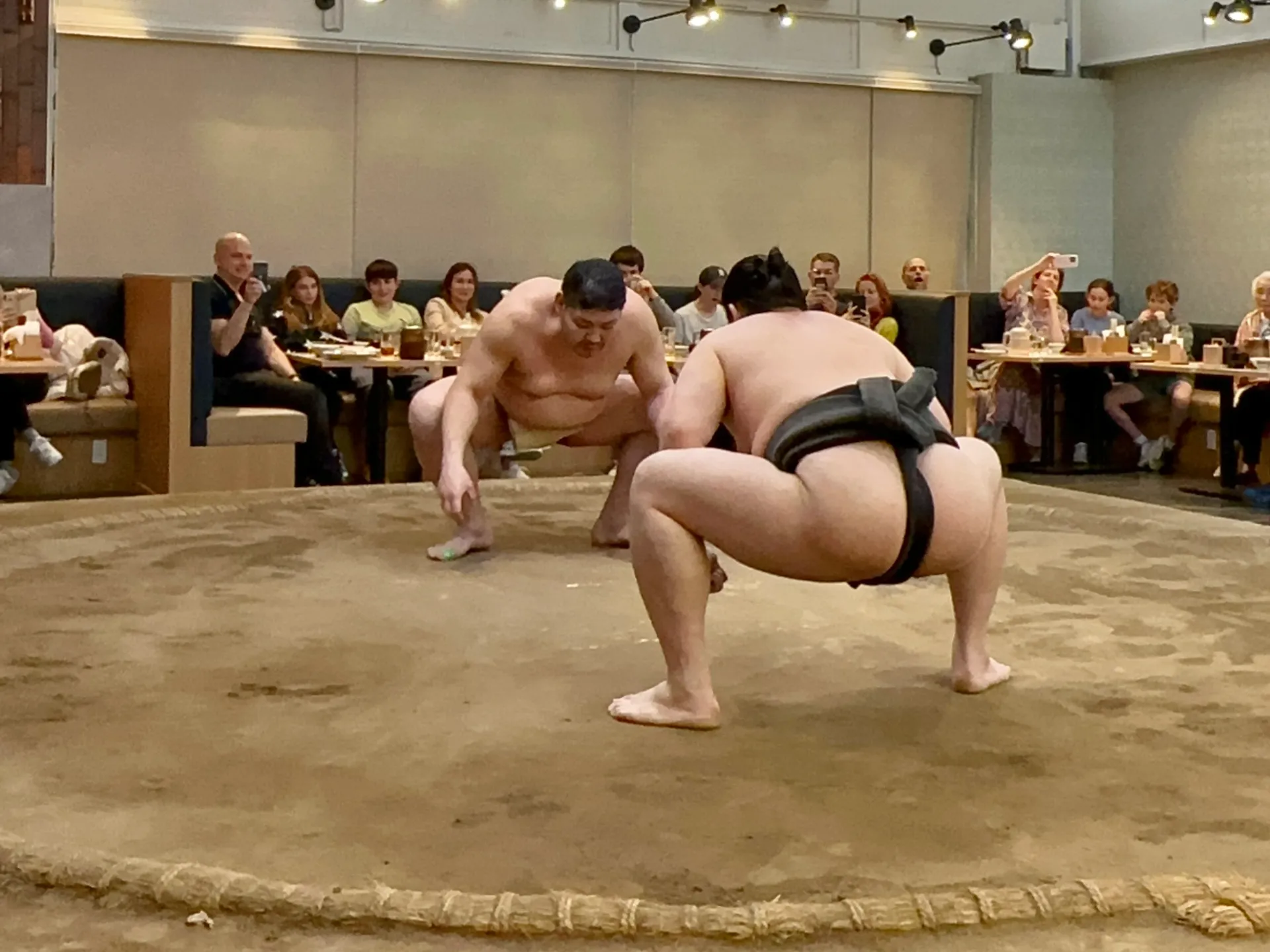 東京の相撲ショーレストランで取組を披露する力士たちと観客